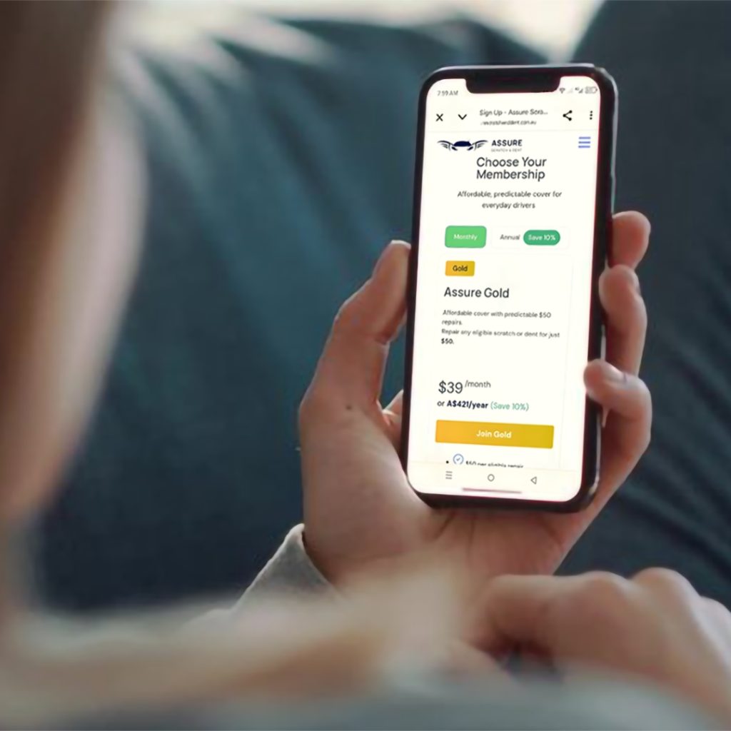 Person holding smartphone displaying Assure membership options page with Gold plan at $39 per month